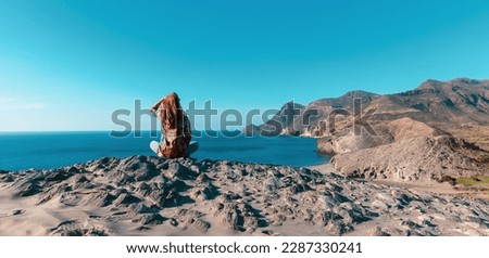 Woman sitting on rock looking at panoramic view of mediterranean sea- Andalusia in Spain