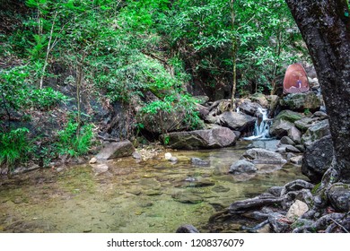 
A woman sitting on the rock at small waterfall - Shutterstock ID 1208376079
