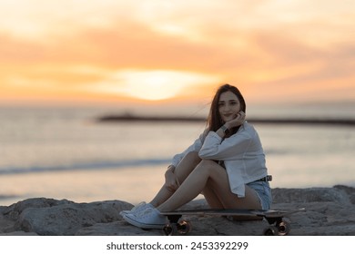 A woman is sitting on a skateboard on a beach - Powered by Shutterstock