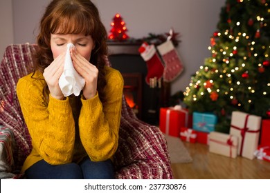 Woman Sitting On Sofa And Blowing Her Nose At Christmas At Home In The Living Room