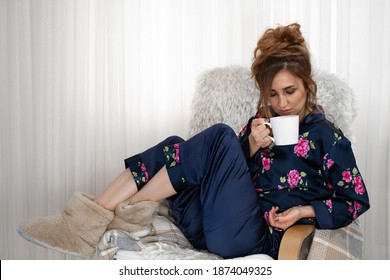 Woman Sitting On Sofa And Drinking Coffee, With Navy Nightgowns And Plush Slippers