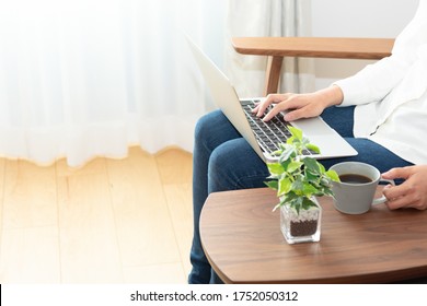 
A woman sitting on a sofa and operating a personal computer