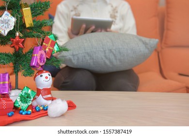 woman sitting on sofa using tablet at home. girl texting message on touchpad during xmas. christmas holiday new year celebration season greetings