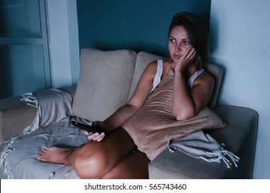 Woman Sitting On Sofa Watching Tv In Dark Room