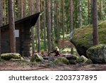 Woman sitting on the Sorsakolu campfire site in the Evo hiking area, Hameenlinna, Finland