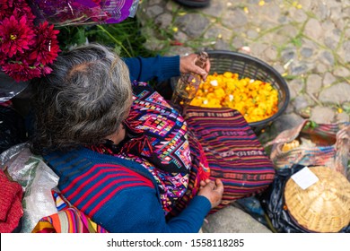 A woman is sitting on the stairs at the Chichicastenango market in Guatemala.