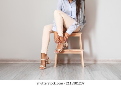 Woman Sitting On Step Stool Near Light Wall