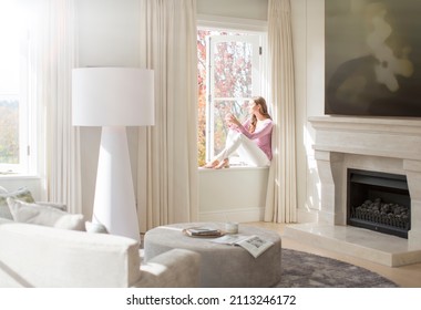 Woman Sitting On Sunny Windowsill