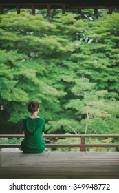 Woman sitting on a temple terrace and looking at a Japanese garden, Kyoto, Japan