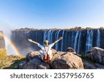 Woman sitting on the top of a rock enjoying the Victoria Falls -  Zimbabwe