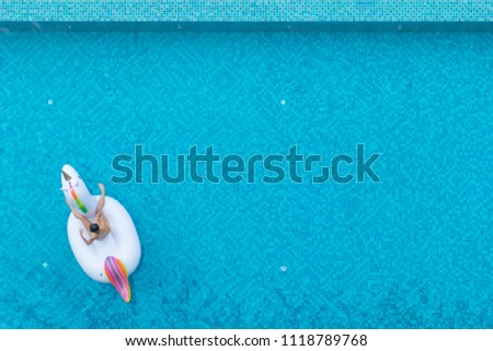 Woman sitting on unicorn raft in blue swimming pool