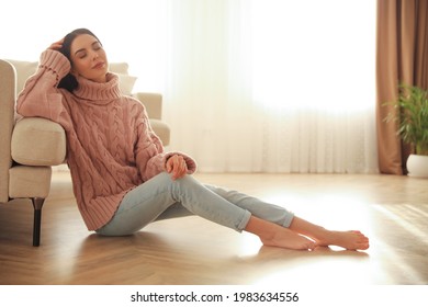 Woman Sitting On Warm Floor In Living Room. Heating System