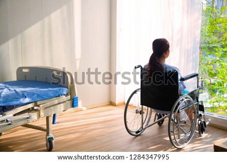 The woman sitting on wheelchair. She is see window with patient bed in hospital.disabled person lonely. Photo concept depression and Patient.
