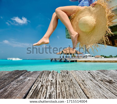 Woman sitting on wooden beach jetty. Summer vacation at Maldives.