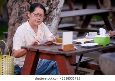 Woman sitting on a wooden bench in a garden restaurant, enjoying her afternoon ginger tea - Powered by Shutterstock