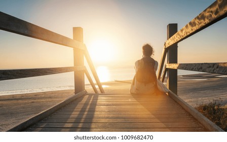 woman is sitting on a wooden path to the Baltic sea at sunset and relaxe the ocean view
