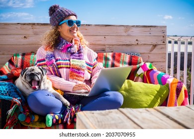 Woman Sitting Outdoor With Dog Smiling And Enjoying Best Friend - Happy Modern People Working Outside With Laptop Computer And Internet Connection - Winter Clothes And Colorful Style