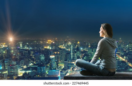 Woman is sitting over the city - Shutterstock ID 227469445