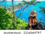 Woman sitting at Ponta da Sapata viewpoint, wearing a straw hat. Capim Açu hiking trail, Fernando de Noronha, Brazil