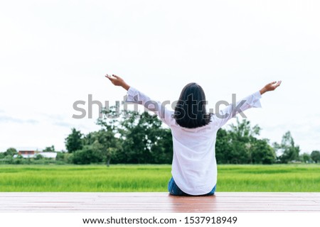 woman sitting and relax on Wood bridge with their legs hanging down, taking pictures from behind.