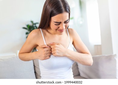 Woman Sitting With Strong Chest Pain And Hands Touching Her Chest While Having Trouble At Home, Heart Attack Or Heart Failure Symptom