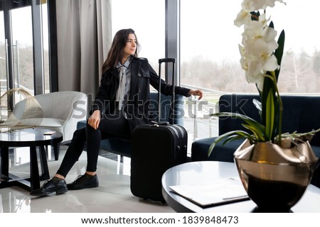 Woman sitting with suitcase in hotel lobby or in an airport lounge