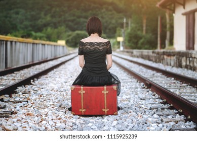 Woman Sitting In A Suitcase In The Train Tracks