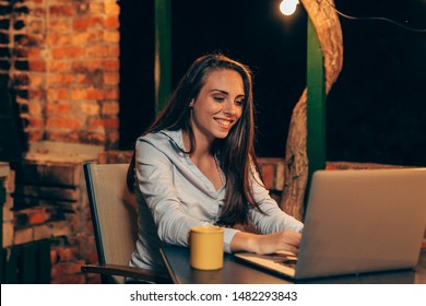 Woman Sitting Table And Using Laptop Computer, At Home Backyard, Night Scene