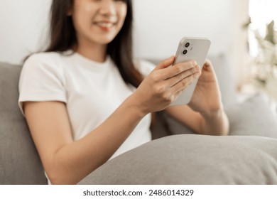 Woman sitting using smartphone on sofa inside home.. - Powered by Shutterstock