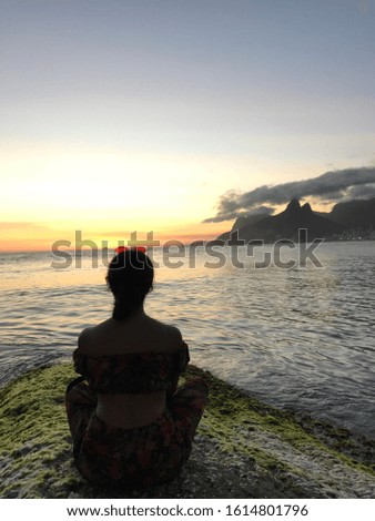 woman sitting watching sunset at sea