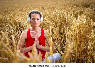 Woman Sitting A A Wheat Field Meditating Wearing Headphones