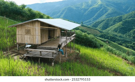 A woman sitting in wooden cabin, playing with cat and looking at a mountain view - Powered by Shutterstock