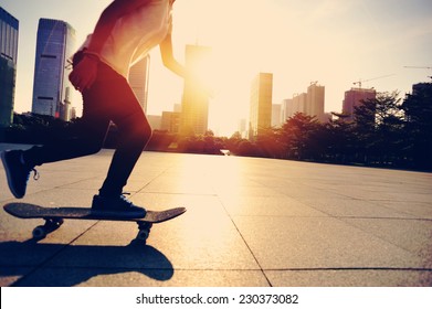 Woman skateboarder legs skateboarding at sunrise city 