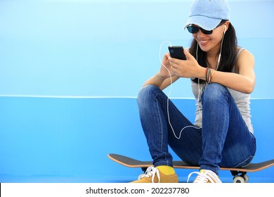 Woman Skateboarder Listening Music From Smart Phone Mp3 Player