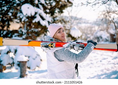 Woman skier carrying skies in snowy nature. Blonde pretty Female going on skiing. Winter ski vacation 