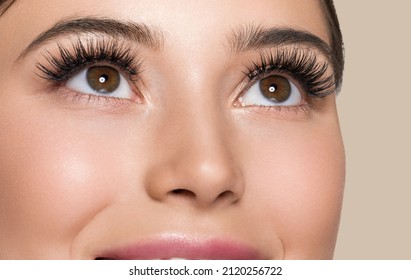 Woman skin face with lashes beautiful eyes healthy hair brunette. Look up. Color background.