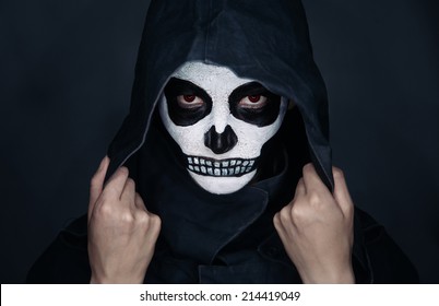 Woman with skull makeup in hood looks at camera, Halloween face art - Powered by Shutterstock