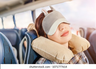 Woman in sleep mask and with pillow travelling in bus