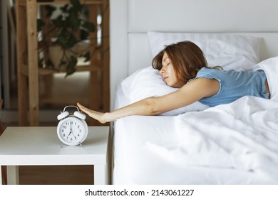 Woman sleep on the bed turns off the alarm clock wake up at the morning, Selective focus.Young woman reaching to turn off alarm clock ,early morning