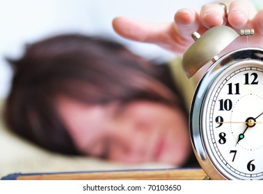 A woman is sleeping with an alarm clock in front - Shutterstock ID 70103650