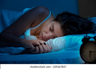 Woman sleeping in a bed in a dark bedroom