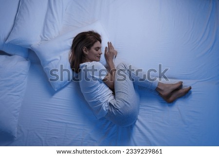 Woman sleeping in bed at night, top view