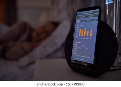 Woman Sleeping In Bed With Sleep Data App Running On Mobile Phone On Bedside