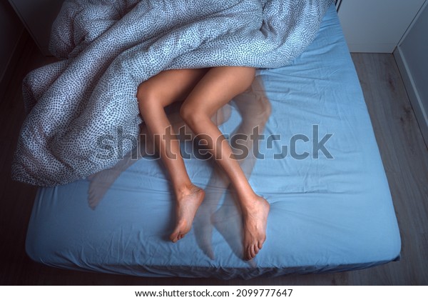 Woman sleeping in the bed and suffering from RLS\
or restless legs syndrome
