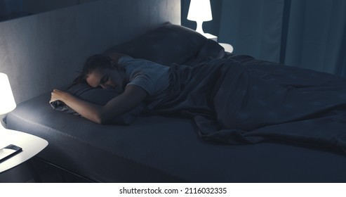 Woman sleeping in her bed at night, she is lying on her stomach