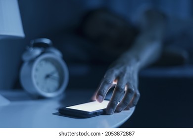 Woman sleeping in her bed and receiving a phone call late at night, she is checking her smartphone - Powered by Shutterstock