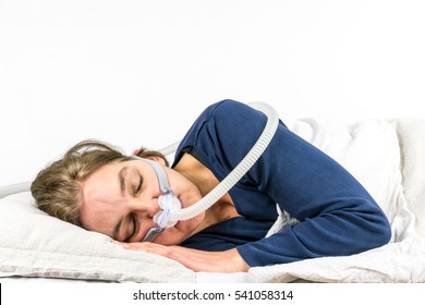 Woman sleeping on her side with CPAP, sleep apnea treatment. Studio portrait white background.