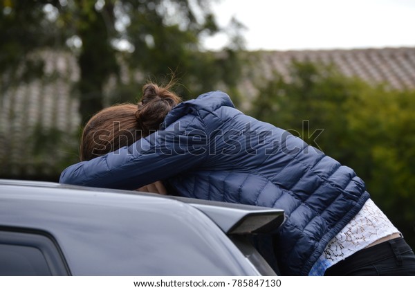 woman\
sleeping on top of a car wearing a blue jacket\
