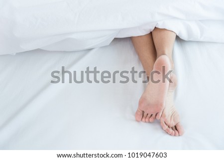 Woman Sleeping show feet on bed white blanket