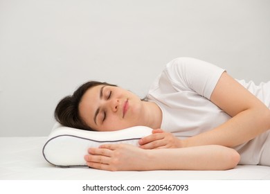 A woman sleeps on an orthopedic pillow made of memory foam, lying on a bed. The correct pillow for a comfortable healthy sleep.